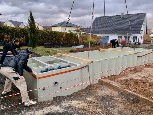 Zwei Arbeiter heben eine Betonplatte auf einer Baustelle an, um sie zu platzieren.